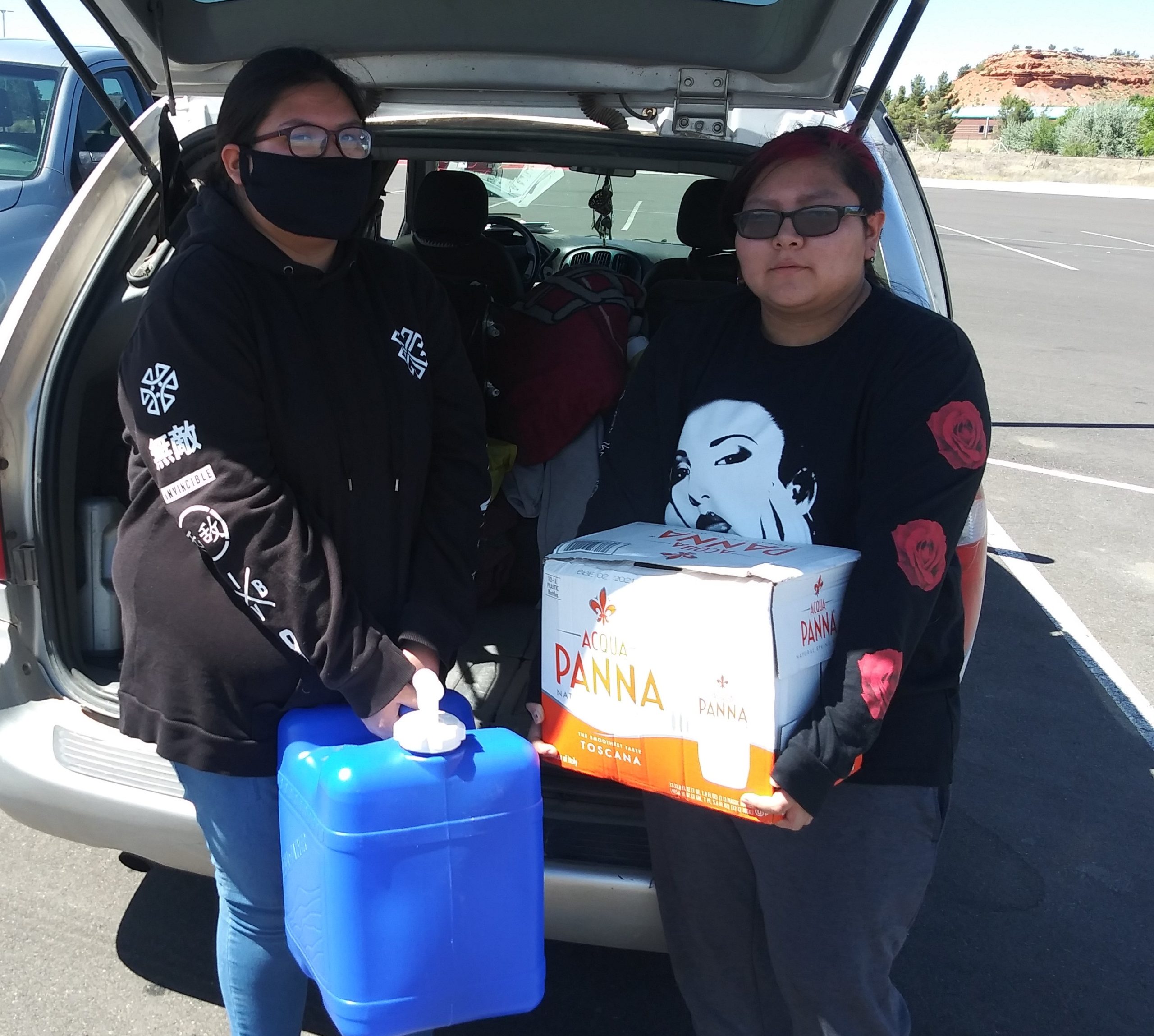 Two members of the Navajo Nation holding water delivered by Heart to Heart International.