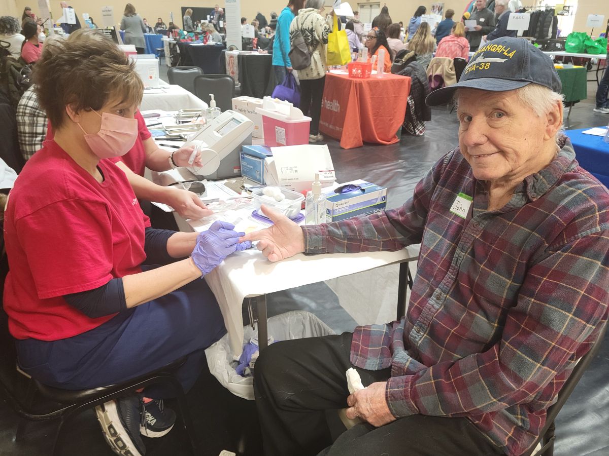 Man receives blood test at community health event.
