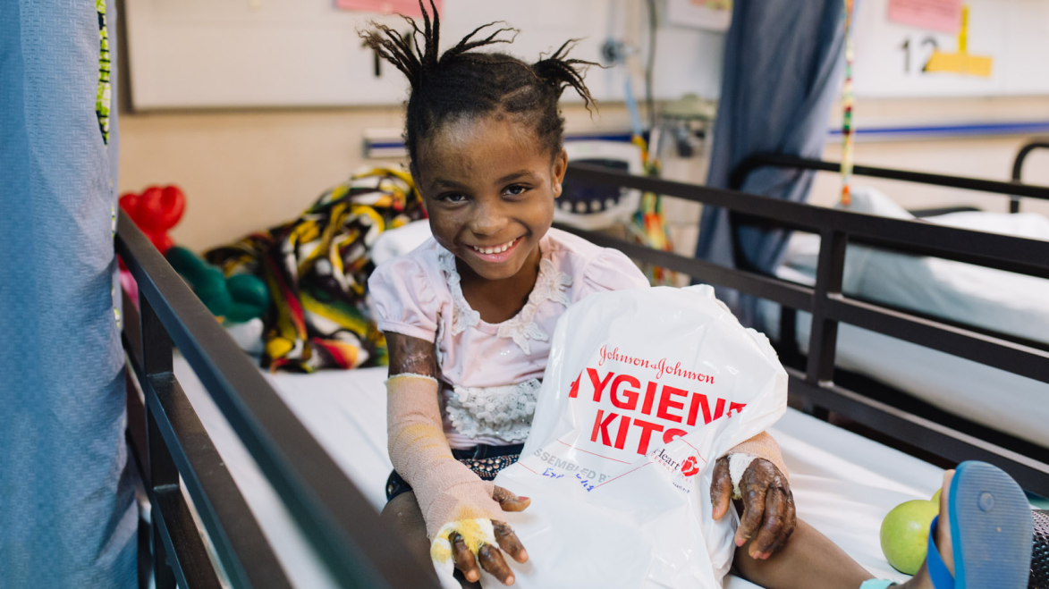 Smiling girl patient on clinic bed with HHI hygiene kit.